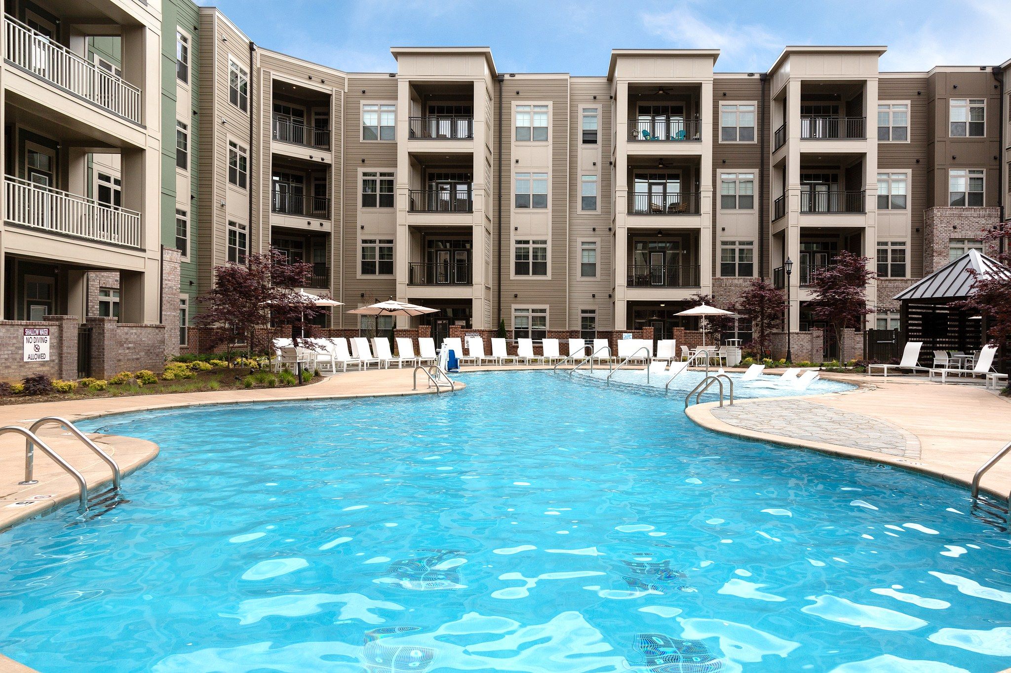 Zero-entry luxury pool with lounge chairs surrounded by apartments