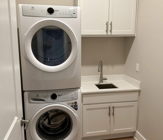 Stacked washer and dryer with small sink beside it at Providence Row Apartments Phase II