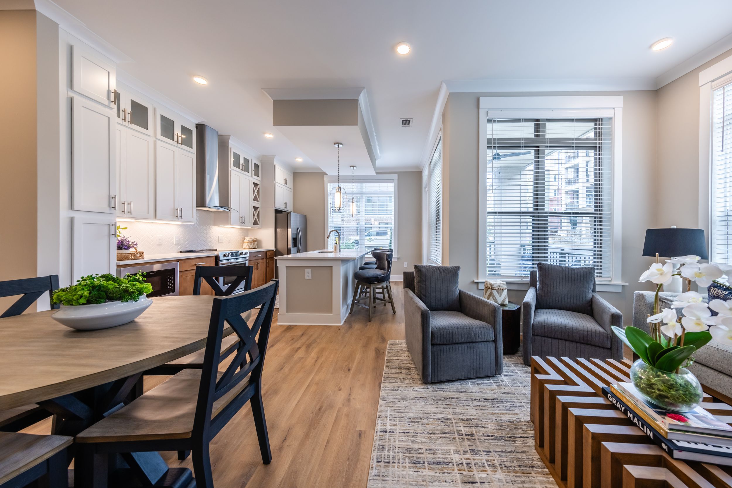 Apartment interior of kitchen with two tone cabinetry, kitchen island, stainless steel appliances, and luxury flooring