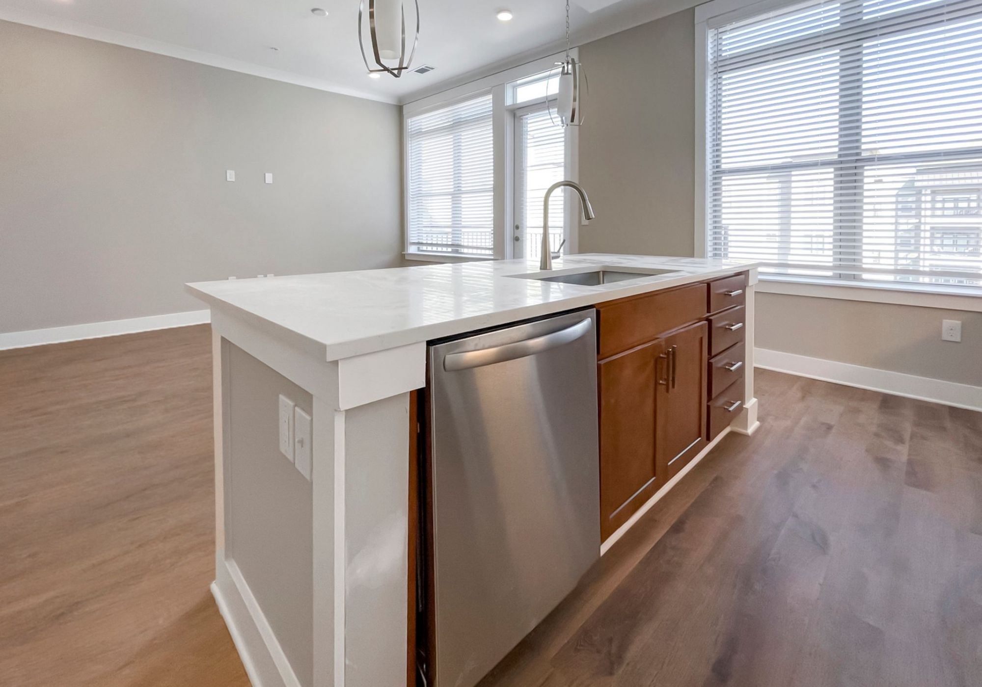 Close up of kitchen island in luxury South Charlotte apartment showing a dishwasher, deep kitchen sink, and cabinet storage