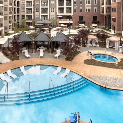 Luxury outdoor pool and hot tub with lounge seating and private cabanas at Providence Row Apartments