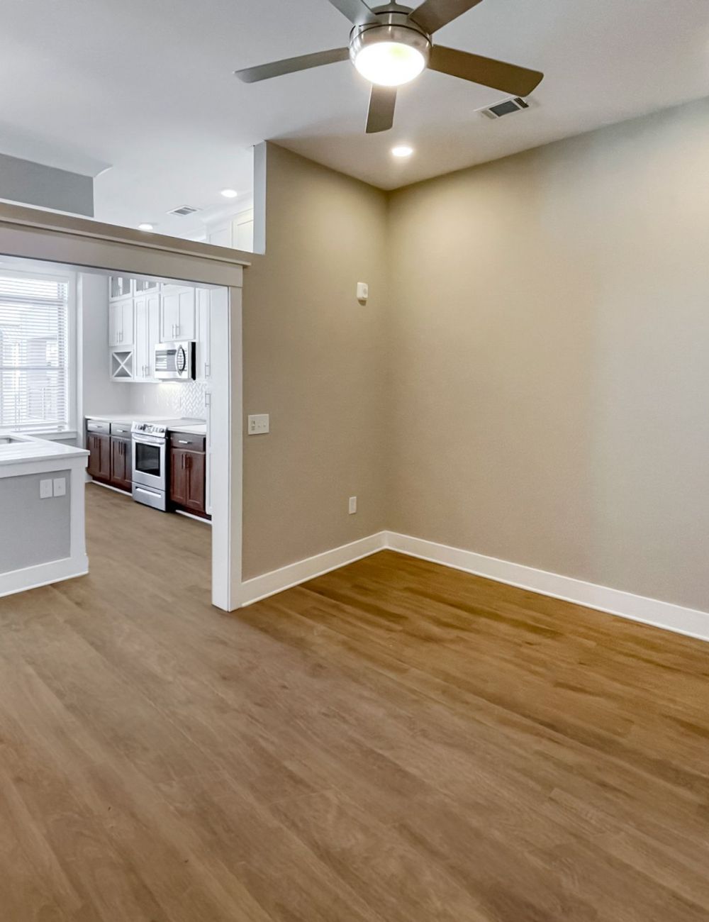 Apartment interior of living space area with ceiling fan and wood-like flooring