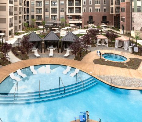 Aerial view of luxury pool and hot tub with lounge seating and cabanas at Providence Row Apartments