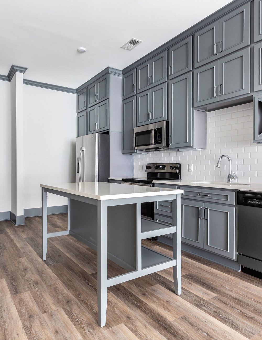 Luxury apartment kitchen interior with stainless steel appliances, beautiful gray cabinetry, and luxury vinyl plank flooring
