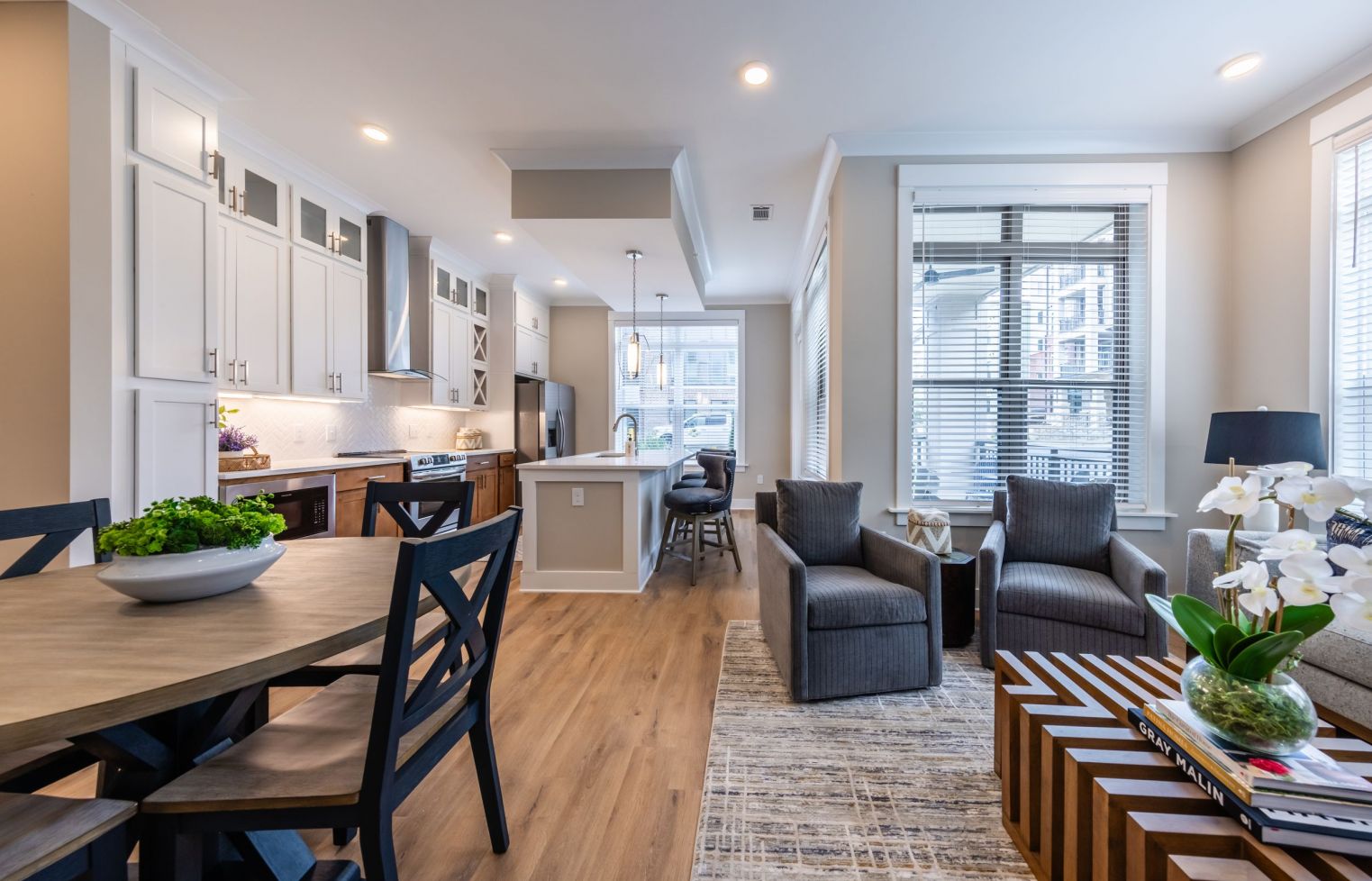 Apartment interior of kitchen with two tone cabinetry, kitchen island, stainless steel appliances, and luxury flooring