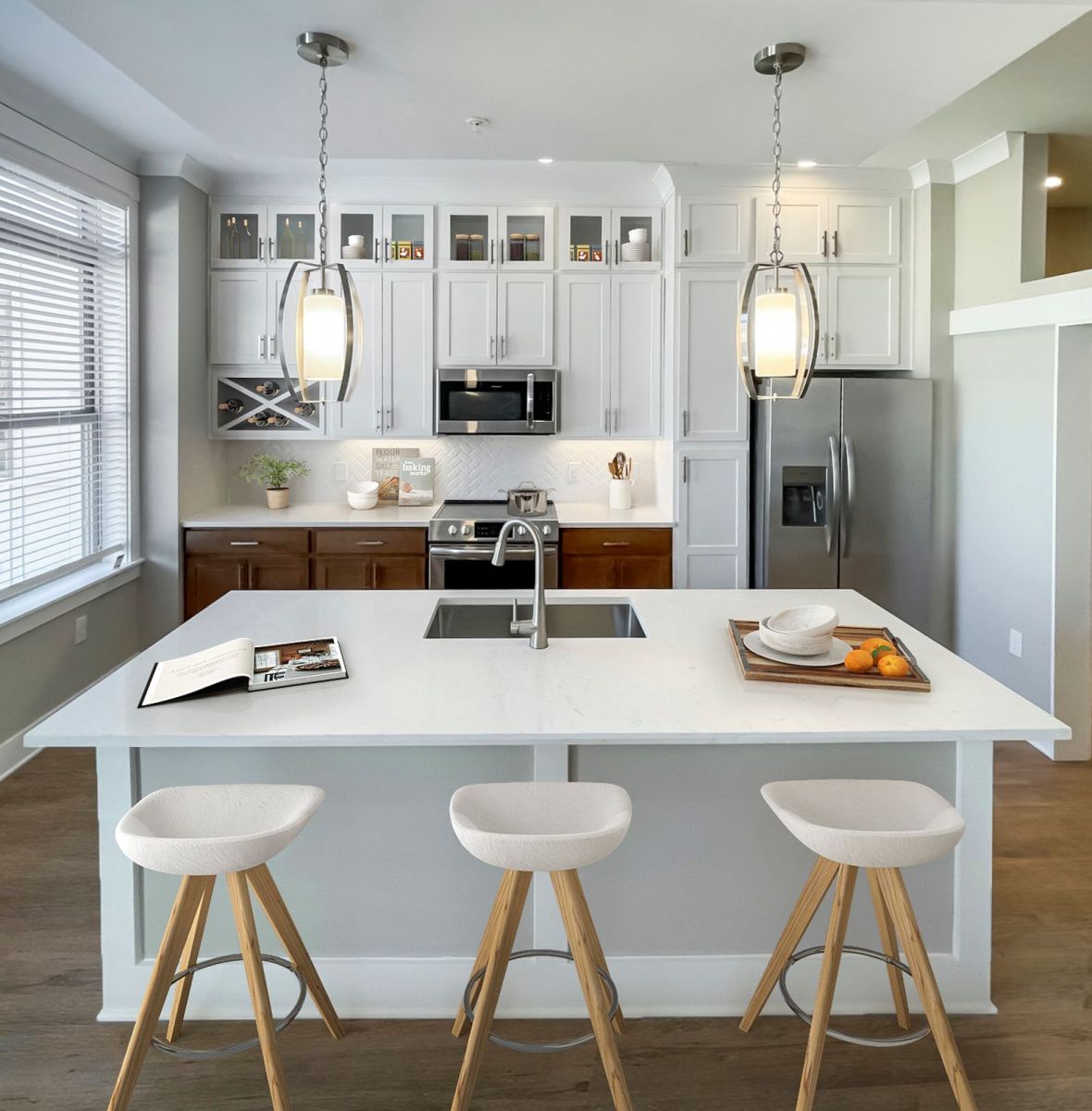 Luxury apartment interior showing kitchen island, luxury vinyl plank flooring, and stainless steel appliances