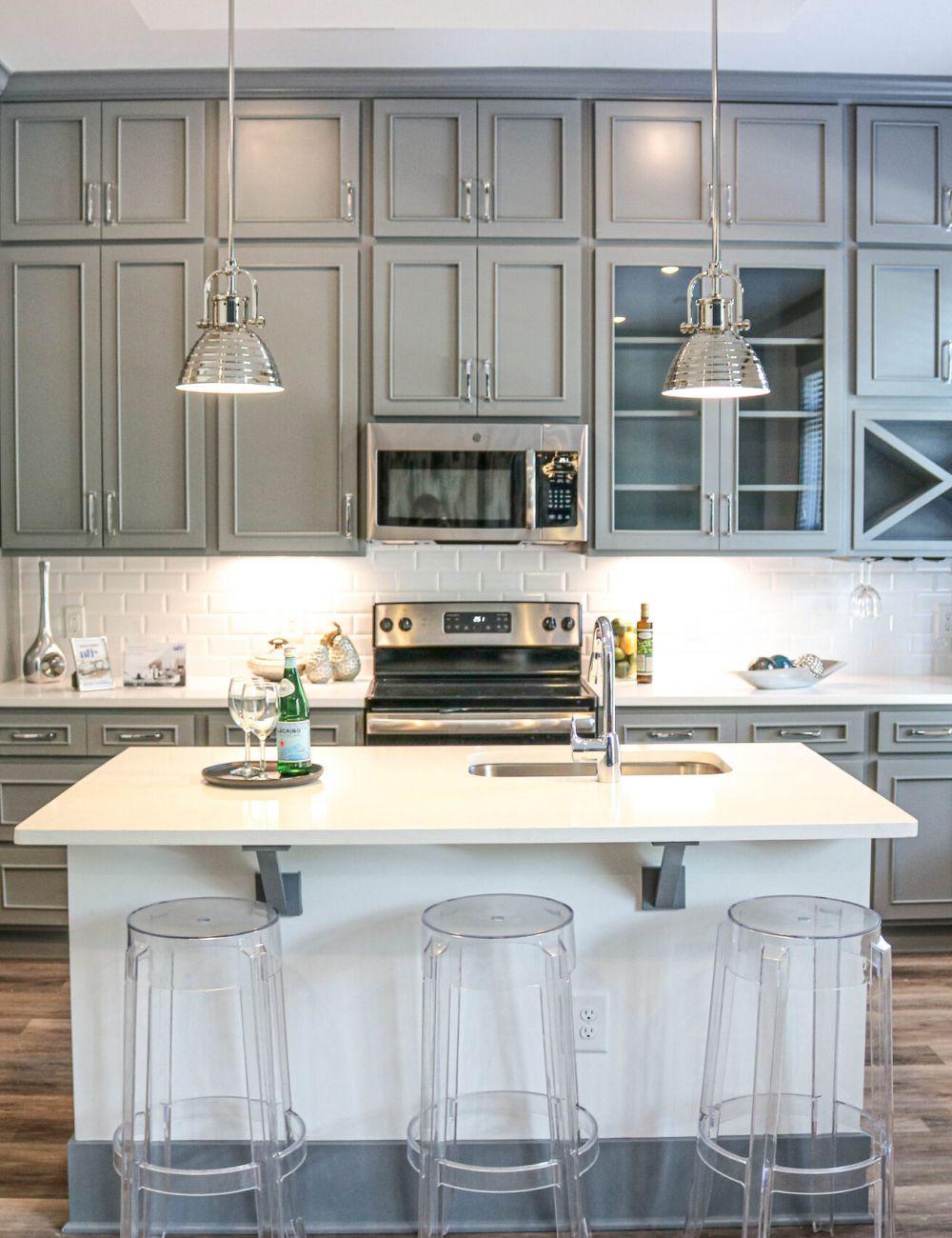 Luxury apartment kitchen interior with stainless steel appliances, beautiful gray cabinetry, and luxury vinyl plank flooring
