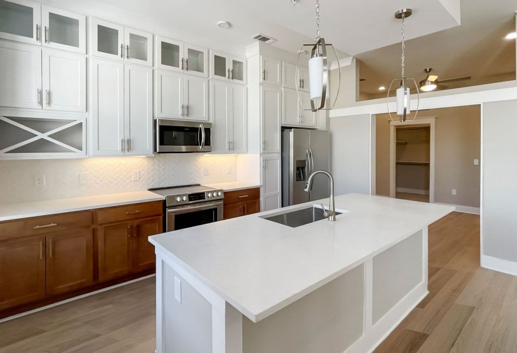 Luxury apartment kitchen with two-tone cabinetry, built-in wine storage, stainless steel appliances, and quartz countertops