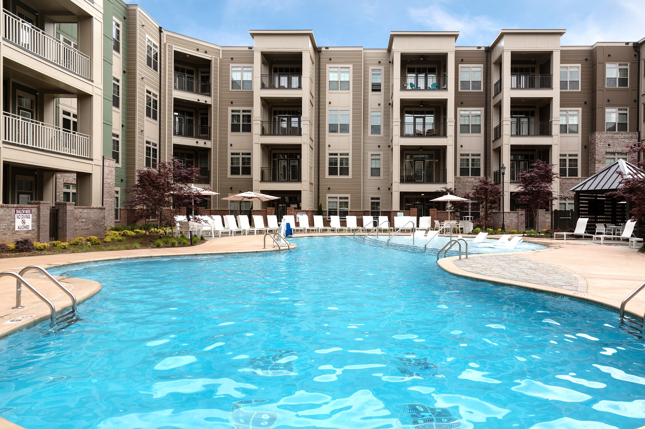 Zero-entry luxury pool with lounge chairs surrounded by apartments