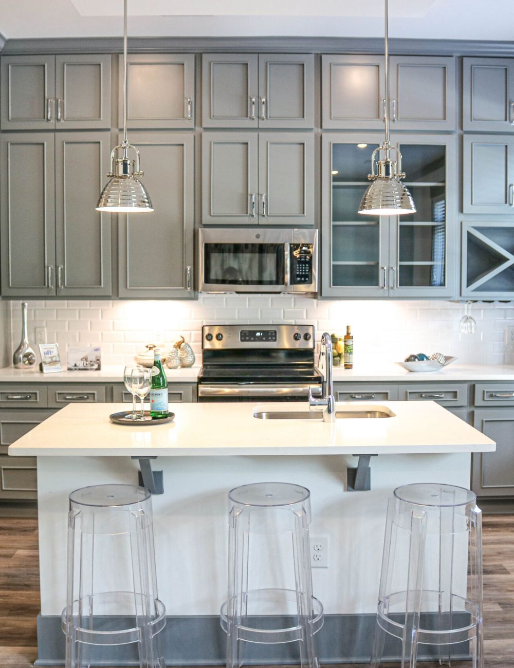 Luxury apartment kitchen interior with stainless steel appliances, beautiful gray cabinetry, and luxury vinyl plank flooring